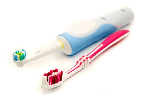 Elektrische Zahnbürste liegt neben Handzahnbürste