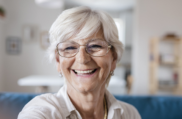 Alte Dame mit Brille lächelt in Kamera