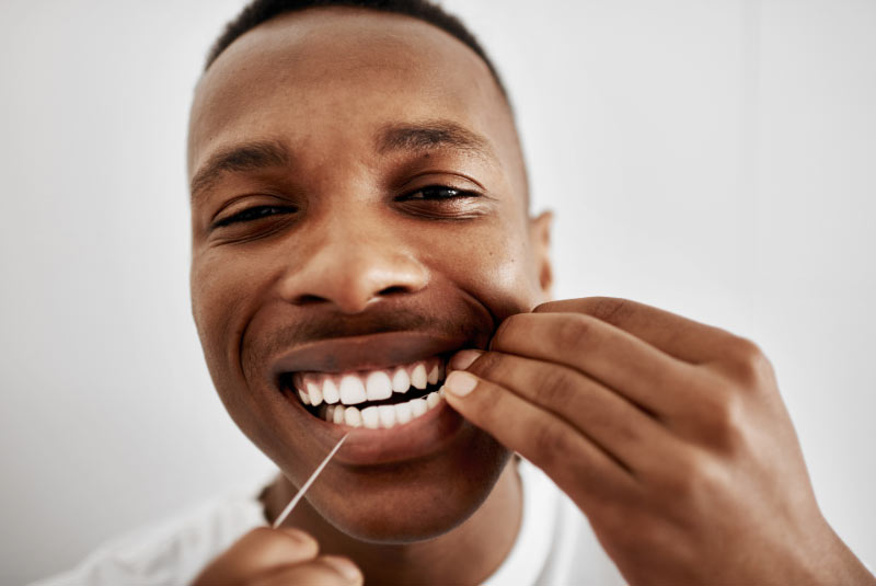 Mann verwendet Zahnseide im Unterkiefer
