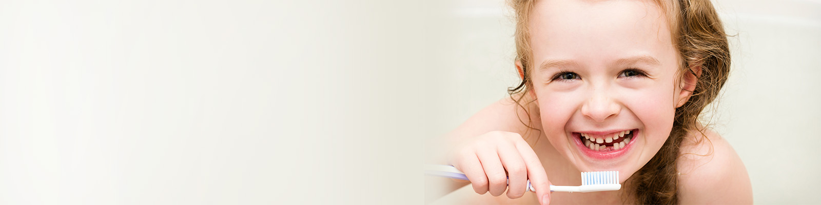 Mädchen mit Zahnlücken hält eine Zahnbürste
