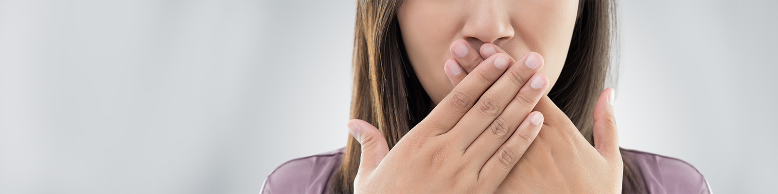 Frau hält sich beide Hände vor den Mund