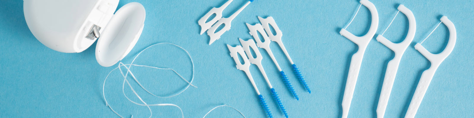 Zahnseide und Dentalbürstchen auf hellblauem Hintergrund