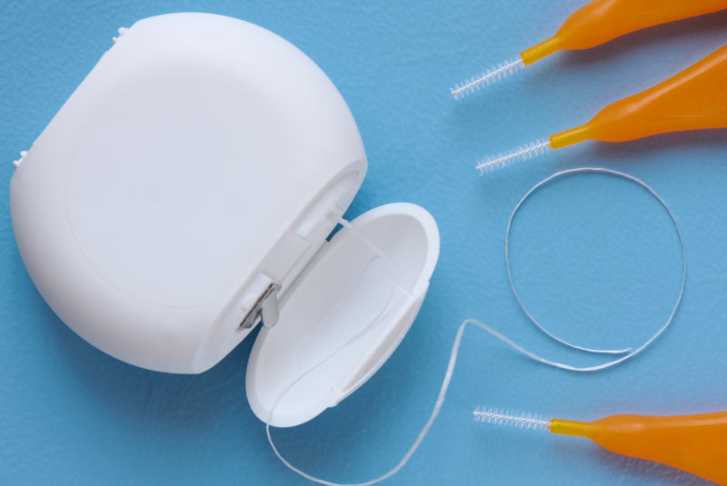 Zahnseide und Interdentalbürsten auf hellblauem Hintergrund